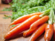 Bunch of fresh carrots with green tops on a wooden cutting board, illustrating foods that support eye health